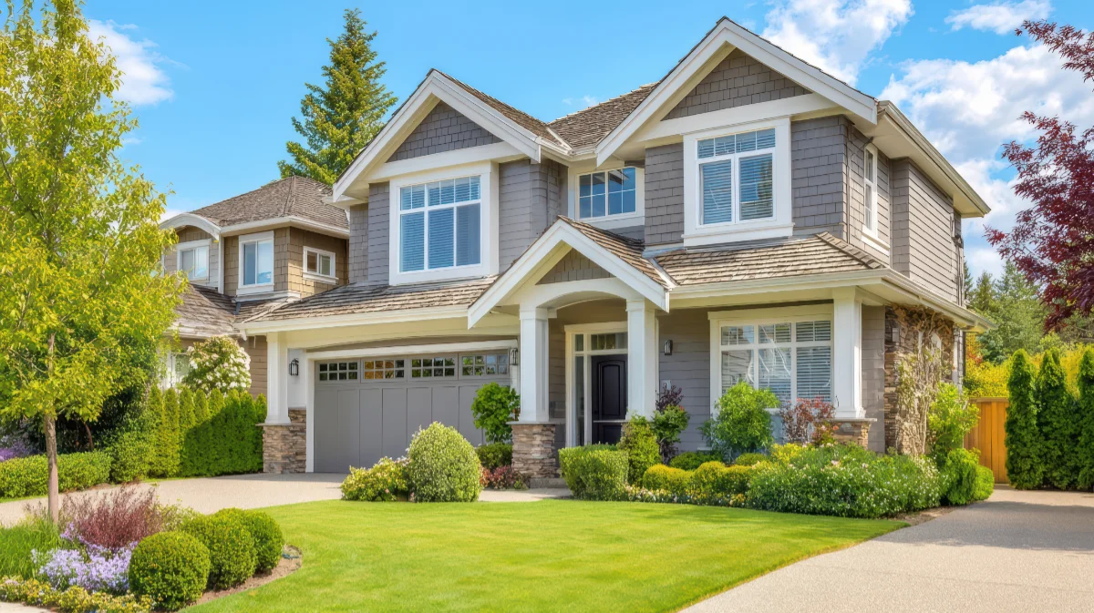 Two-story gray suburban house with white trim, a covered entry, and a manicured front lawn and driveway.